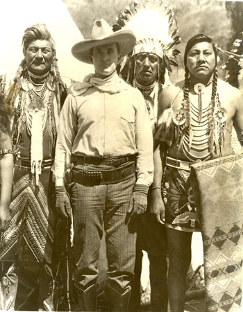 Tim McCoy recruiting among the Bannock Indians at Fort Hall, Idaho, in 1922 for Jesse Lasky's "The Covered Wagon" ('23). The man on Tim's right wears the typical old time Bannock hairstyle. The man on Tim's left, Black Thunder, has his left hand wrapped in a blanket to hide his bear claw.